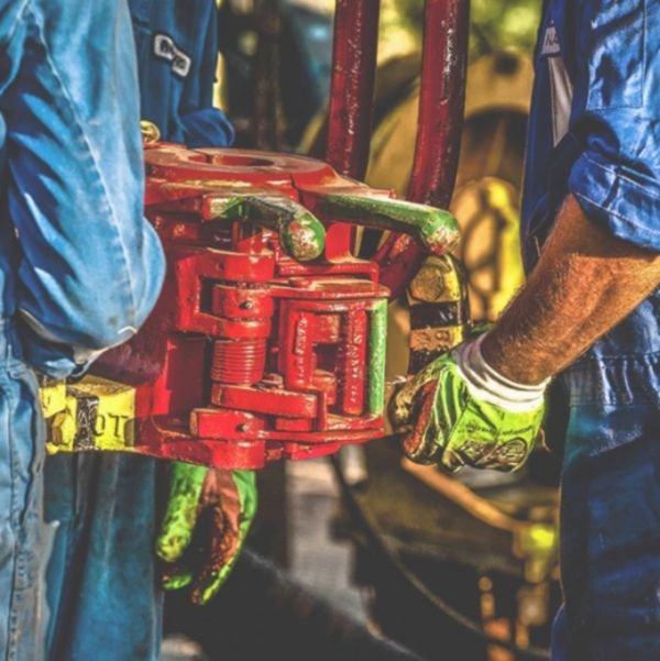 Operarios con guantes de protección sujetando una herramienta hidráulica en una instalación industrial