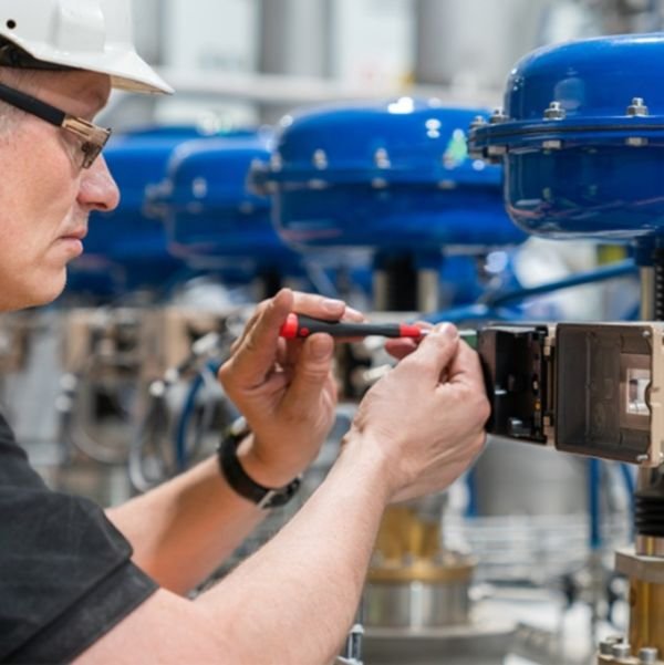 Técnico ajustando el posicionador de una válvula de control con actuador neumático
